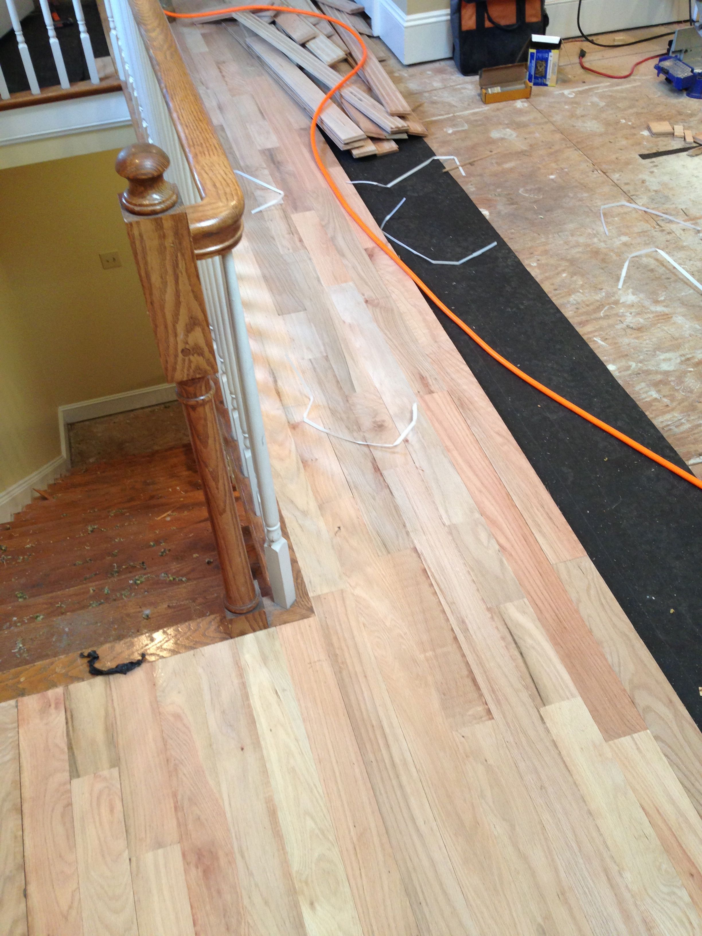 A photo of red oak hardwood installation over tar paper and plywood subflooring.