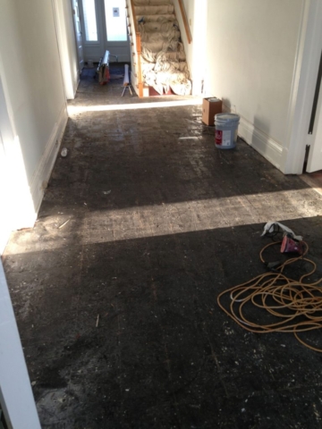 A picture of a tar covered hardwood floor after tile was removed.