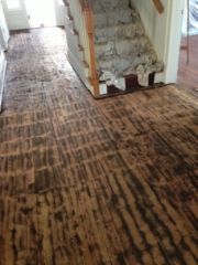 Pictured are hardwood floors partially covered with tar.