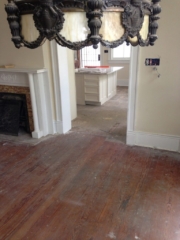 Hardwood floors in a living area and kitchen prior to being refinished.