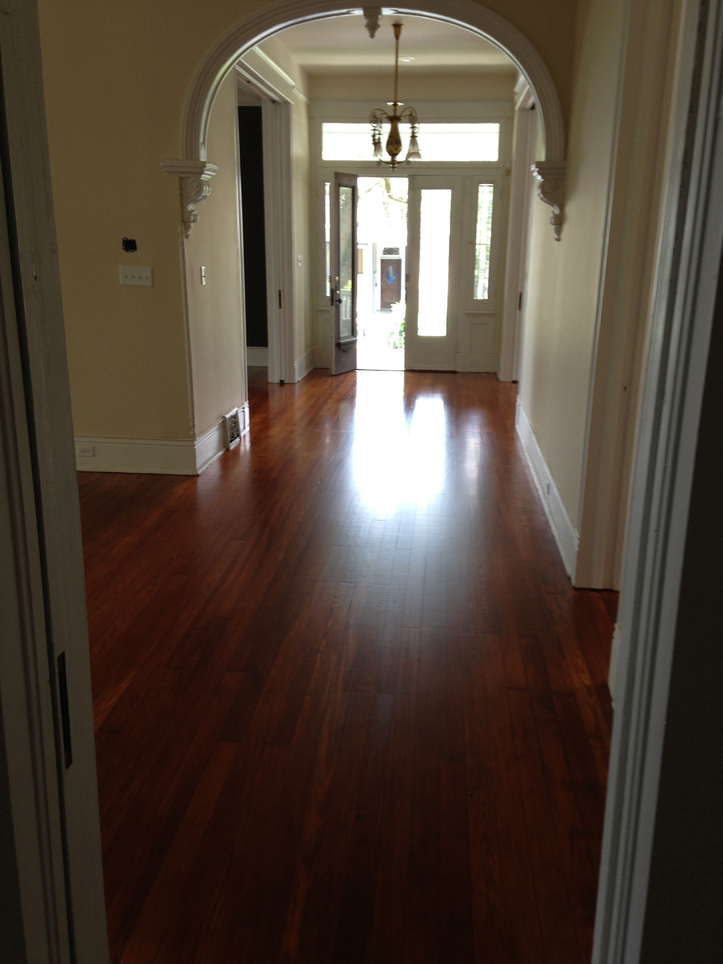 Refinished hardwood flooring in an arched foyer at front entrance