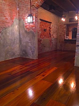 This is a photo of a historic cottage with wide planked shiny floors with shades of red and dark brown.