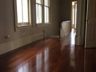 This is a hallway with a stairwell of refinished glossy pine floors.