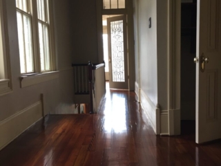 This is a hallway with a staircase of refinished glossy pine floors.