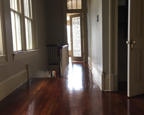This is a hallway with a staircase of refinished glossy pine floors.