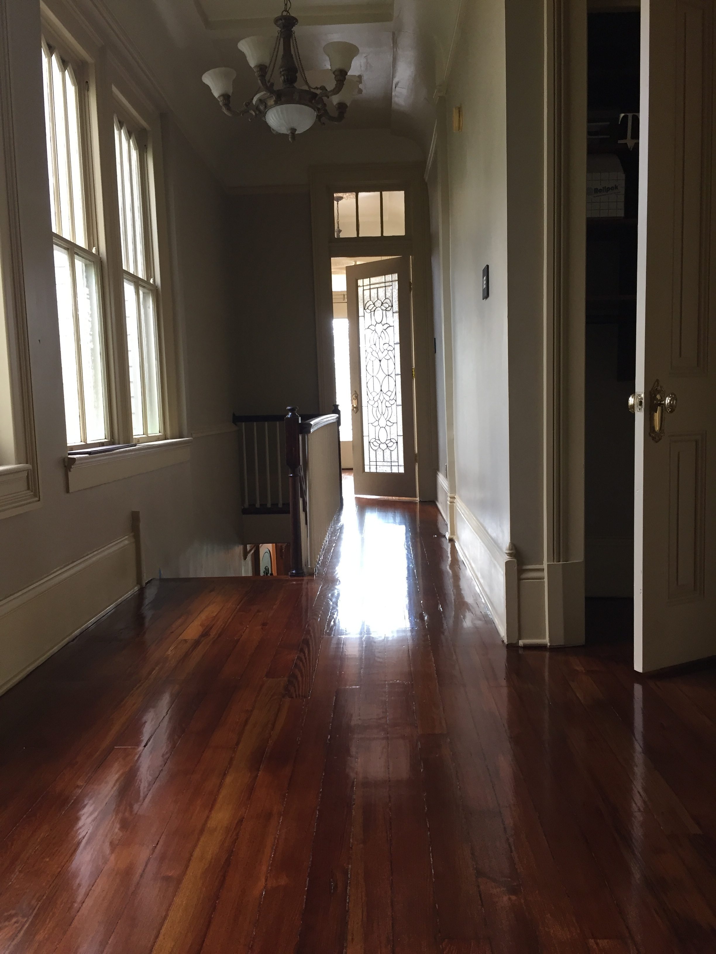 This is a hallway with a staircase of refinished glossy pine floors.