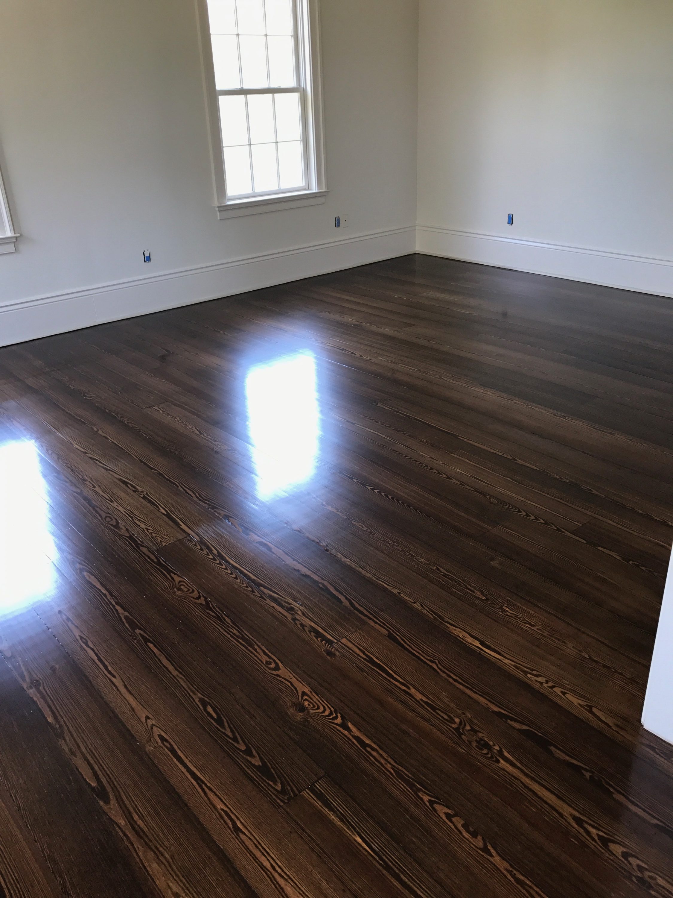 Pictured is a room with dark stained red pine hardwood flooring. The floors are glossy with the contrasting grain visible.