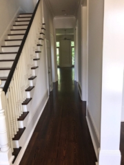 Pictured is a hallway with red pine floors with a dark stain.