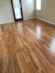 Pictured are red oak floors with a natural finish. The contrasting colors in the wood grain are eye catching with shades of red tones, browns, and creamy white.