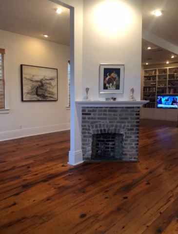 A living room photo with medium colored hardwood flooring prior to bleaching to a lighter color.