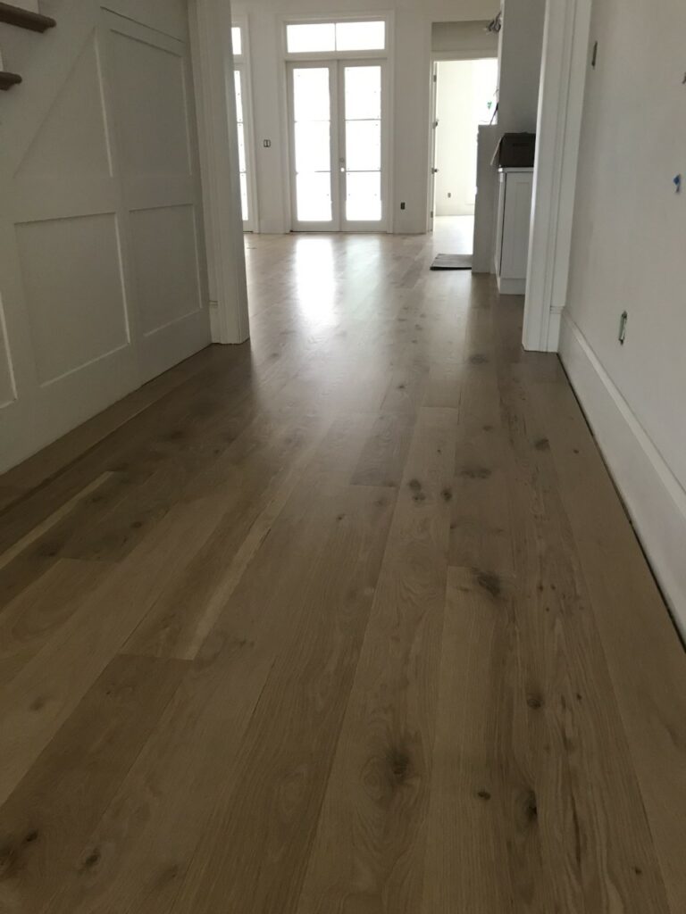 This is a photo of a hallway with white oak flooring with a satin finish. It has a weather washed appearance.