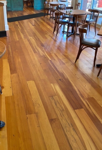 Photo of refinished antique heart of pine floors in a restaurant. Tables and chairs set up for dining.